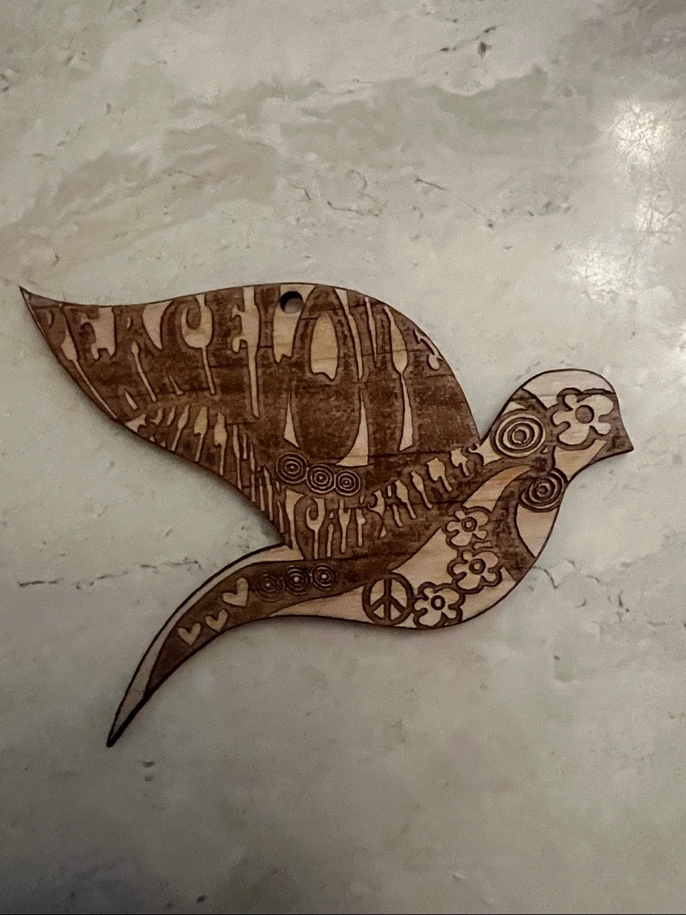 Wooden dove ornament featuring engraved peace and floral motifs